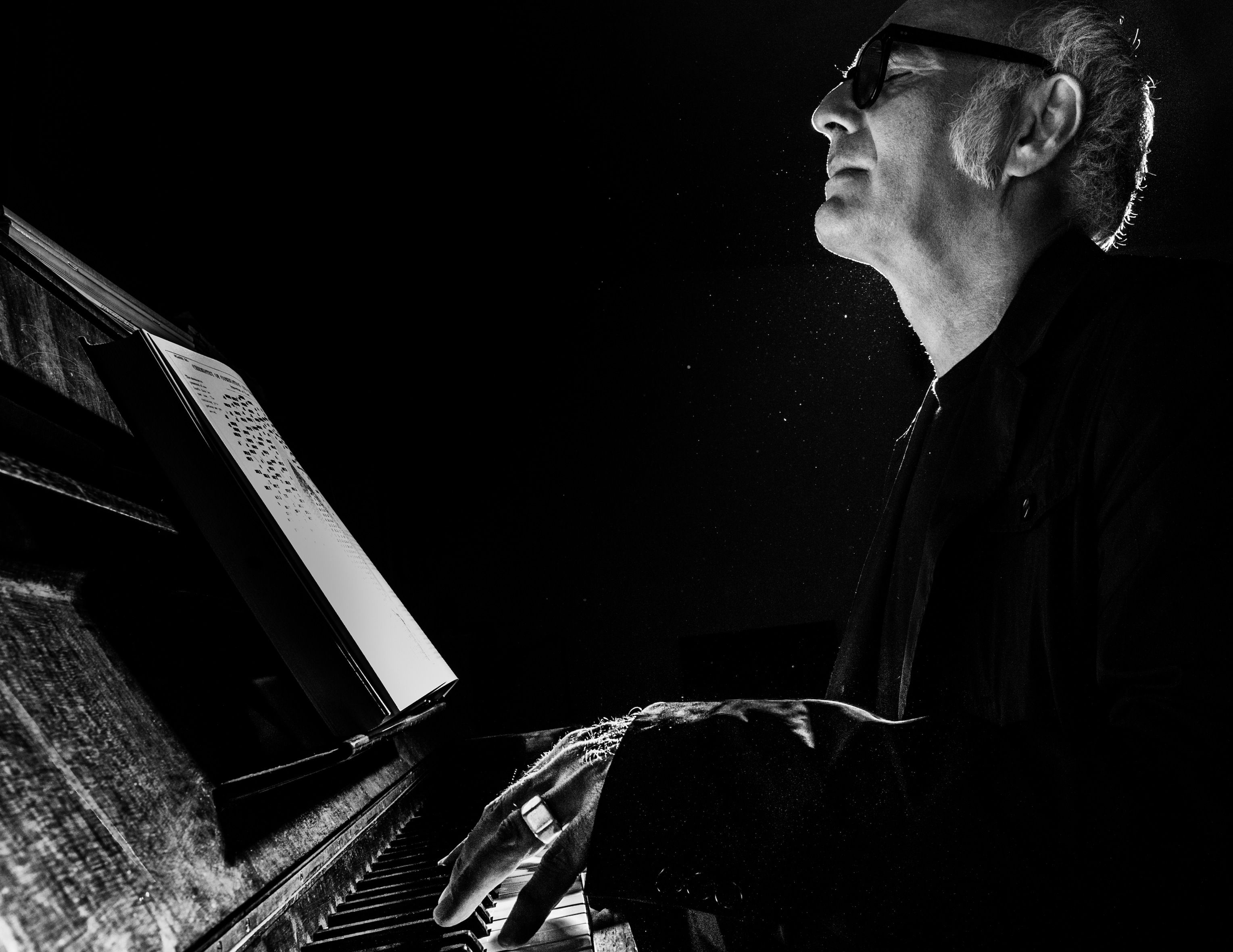 Ludovico Einaudi playing piano, black and white photo